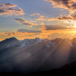 Plays of light at sunset through the clouds. Alps, Lombardy, Italy