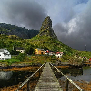 A small wooden bridge creates a great leading line towards the rugged peak and the colorful houses in Reine. Lofoten Islands, Norway