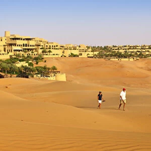 Tourists wander through dunes outside the desert luxury hotel Anantara Qasr Al Sarab