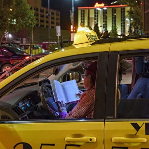 USA, Nevada, Reno, woman cabbie reading in cab at night
