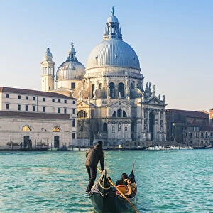 Venice, Veneto, Italy. Tourists on a gondola over the Grand Canal towards the Salute
