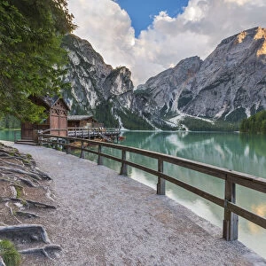 A view of Croda del Becco and footpath and house of boats from Braies lake at sunset
