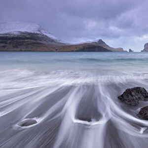 Waves crash onto the black sandy beach at Bour on the island of Vagar in the Faroe Islands, Denmark, Europe. Winter (March) 2015