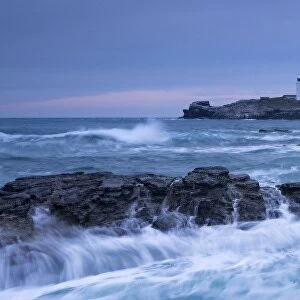Waves crash around the rocks near Godrevy Lighthouse, Cornwall, England. Winter