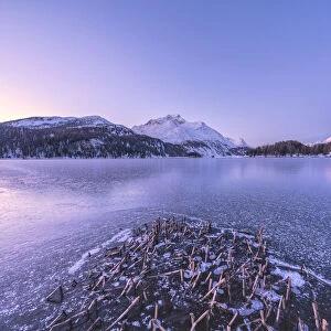 Winter sunrise over the snow capped Piz Da La Margna and frozen Lake Sils, Graubunden