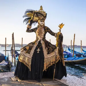 A woman in a magnificent costume poses in front of Gondolas during the Venice Carnival