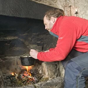 A man cooking in Peanmeanach Bothy near Mallaig in Scotland