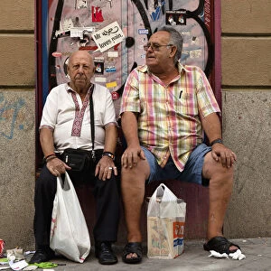Spain, Madrid, Two visitors to the El Rastro Flea market take a rest from shopping