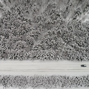 An aerial view shows a car driving along a forest road after snowfall outside Krasnoyarsk