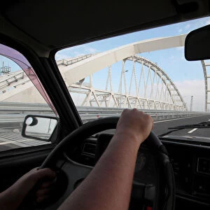 A driver operates a car on a bridge, which was constructed to connect the Russian