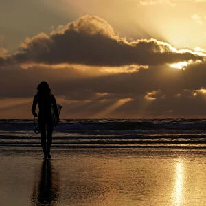 A female surfer walks out into the waves at Cardiff State Beach in Encinitas, California