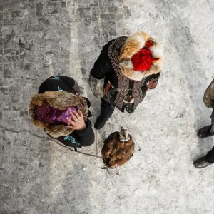 Hunters stay next to a tamed golden eagle during an annual competition at Almaty