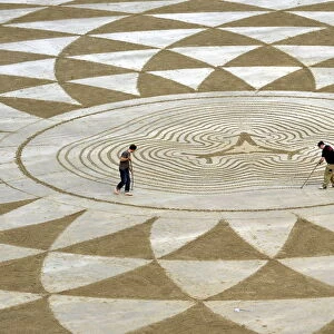 Local artists draw patterns in the sand at low tide on North Beach, Tenby, South Wales