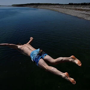 A man jumps into the sea at Salthill beach during sunny weather in Galway