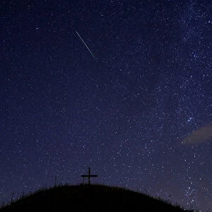 A meteor streaks past stars in the night sky above Leeberg hill during the Perseid meteor