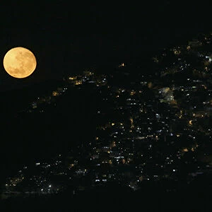 The moon sets behind the Vidigal favela in Rio de Janeiro