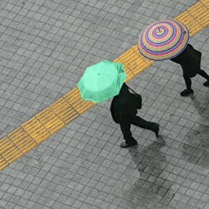 Pedestrians holding umbrellas walk on a street in the rain in central Seoul