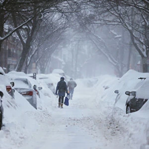 Pedestrians make their way along a snow covered street during a winter snow storm in