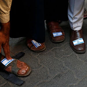 People stick Israeli flags on their shoes during a protest against the visit of Israeli