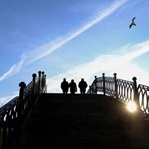 People walk along a bridge at a sunny day in Moscow