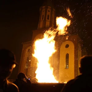 People watch burning Yule logs in front of the Church of the Holy Mother of God during