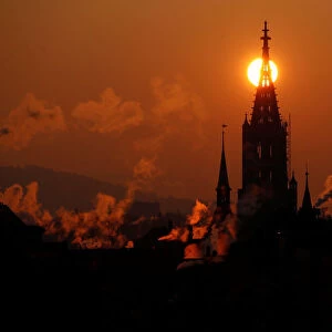 The sun rises behind the Muenster Cathedral during a cold morning in Bern