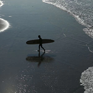 Surfer heads home after riding the morning waves in Oceanside, California