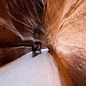 Tourists ride a horse-drawn cart during a tour in the ancient city of Petra, south