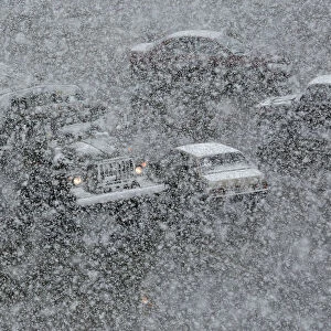 Vehicles drive along a road during a heavy snowfall in the Siberian town of Divnogorsk