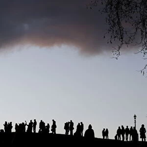 Visitors to Primrose Hill take in the early evening views over central London
