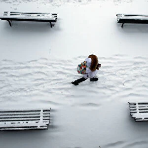A woman walks past snow covered benches in a park in Lausanne