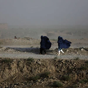 Women walk on a windy day outside Kabul