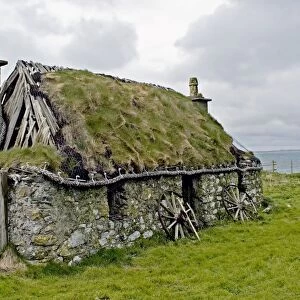 Derelict croft cottage near coast, thatch retained with wire netting and rope, South Uist, Outer Hebrides, Scotland