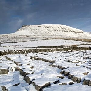 View of snow covered limestone outcrop and drystone walls, with Pen-y-ghent in background, Yorkshire Dales N. P