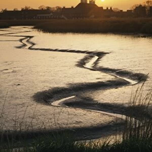 View of tidal river at low tide and arts complex on riverbank at sunset, Snape Maltings, River Alde, Snape, Suffolk