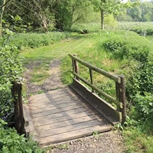 Wooden footbridge on footpath beside lowland river, River Rattlesden, Stowmarket, Suffolk, England, april