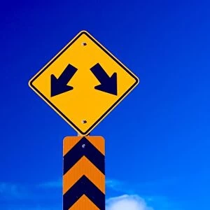 a double arrow traffic sign with a blue sky behind