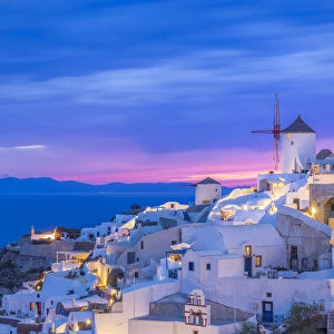 Europe, Greece, Oia. Greek Orthodox church and village at sunset