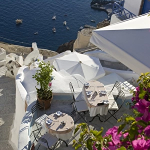 Greece, Santorini, Thira, Oia. Looking down on patio tables set for dinner