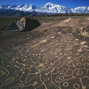 USA, California, Bishop. Curvilinear abstract-style petroglyphs and Eastern Sierra Mountains