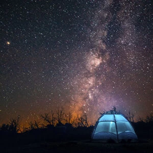 USA, California, Mojave Desert. An illuminated tent against a starry sky and the Milky Way