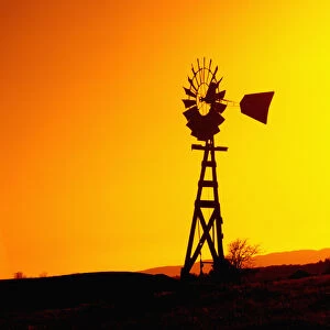 A wooden windmill silhouetted agains the setting sun