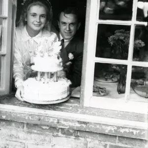 Bride and Groom at the window, displaying their wedding cake