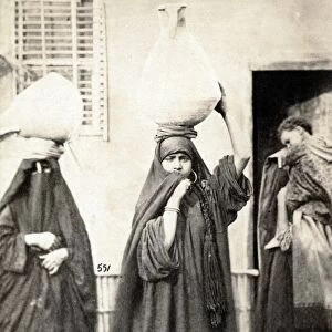 CAIRO: WOMEN. Two women carrying urns on their heads and another woman with a child on her back