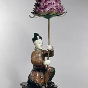 Carved wood and ivory statuette from the reign of Ch ien Lung, depicting a kneeling European holding an enamel lotus, Buddhist symobl of purity. Ching Dynasty, 1736-1796