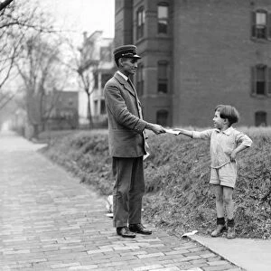 CHRISTMAS, 1920. A boy handing a mail carrier a letter for Santa Claus. Photograph