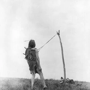 CROW SUN DANCER, c1908. A Crow man tethered to a pole, secured by leather straps