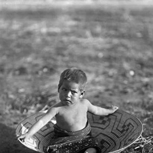 CURTIS: MARICOPA CHILD. A Maricopa Native American child sitting in a basket in