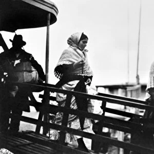 ELLIS ISLAND: IMMIGRANTS. Immigrants walking down the gangplank from a ferry boat at Ellis Island