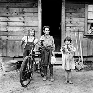 FARM CHILDREN, 1939. Three farm children with a bicycle, Thurston County, Washington State. Photograph by Dorothea Lange, August 1939
